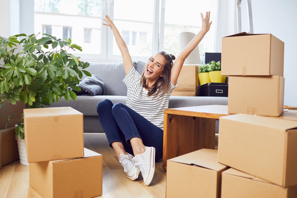 Student celebrating moving into new accommodation whilst surrounded by boxes